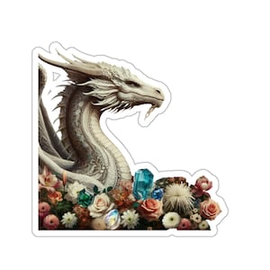 May include: A sticker featuring a white dragon with intricate details, surrounded by colorful flowers and gemstones. The dragon's head is in profile, with its gaze directed to the right. The flowers include roses and daisies, and the gemstones are various colors.