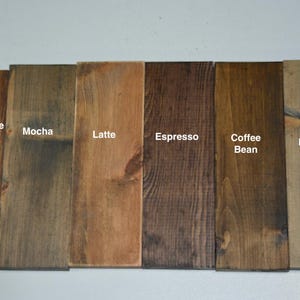 K&ouml;nnte beinhalten: Sechs Holzproben, die in verschiedenen Braunt&ouml;nen gebeizt sind und mit "Chocolate Latte", "Mocha", "Latte", "Espresso", "Coffee Bean" und "Barnwood" beschriftet sind.