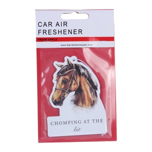 May include: A white car air freshener with a brown horse head illustration. The text "CAR AIR FRESHENER" is printed in black at the top. The text "FRESH APPLE" is printed in red below the main text. The text "www.barreldownsouth.com" is printed in black below the red text. The text "CHOMPING AT THE bit" is printed in black at the bottom of the air freshener.