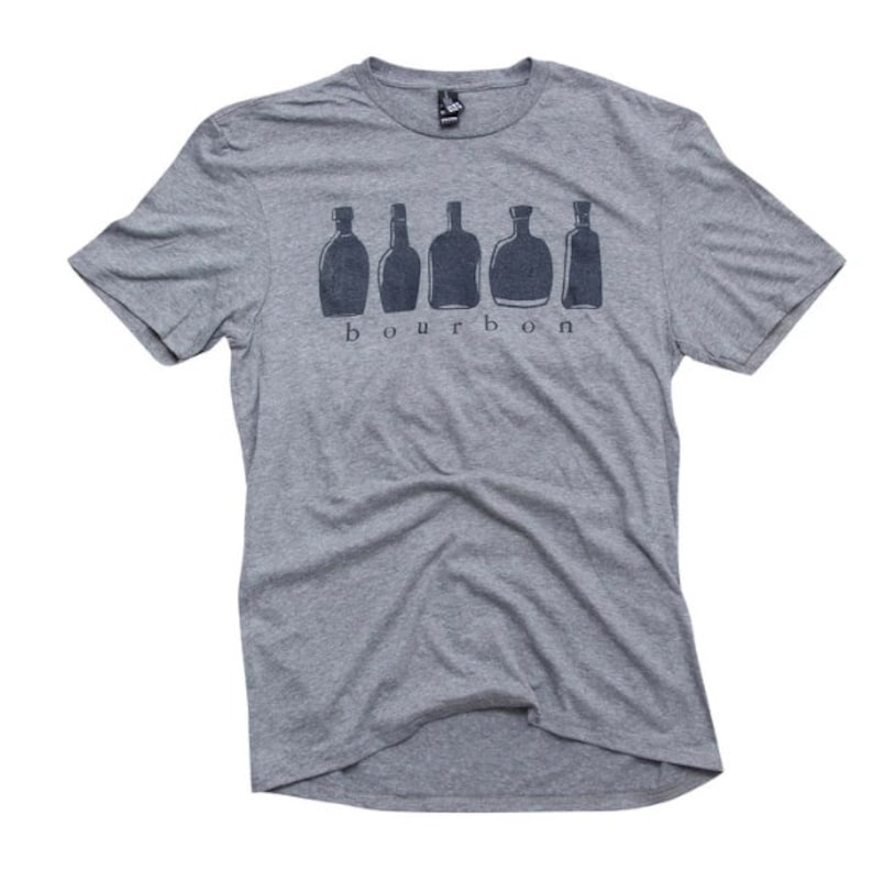 Puede incluir: Una camiseta gris jaspeada con un gr&aacute;fico de seis botellas de bourbon y la palabra "bourbon" impresa debajo de las botellas.