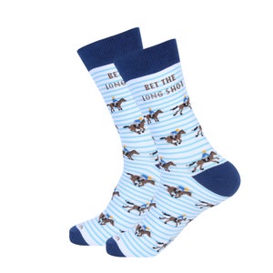 May include: A pair of novelty socks with a horse racing theme. The socks are white with light blue horizontal stripes and feature illustrations of horses and jockeys. The text "BET THE LONG SHOT" is printed on one sock, and "BE LONG" on the other.