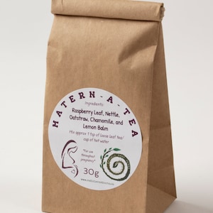May include: A brown paper bag with a white label that says "MATERN-A-TEA" and lists the ingredients: Raspberry Leaf, Nettle, Oatstraw, Chamomile, and Lemon Balm. The label also says "Mix approx 1 tsp of loose leaf tea/cup of hot water" and "For use throughout pregnancy". The bag contains 30g of tea.