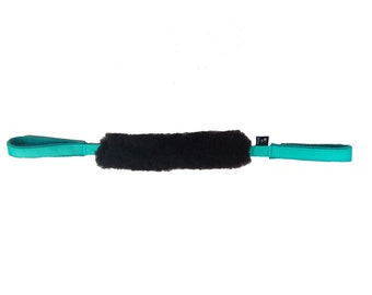 May include: A brown sheepskin grooming brush with teal straps. The brush is designed for horses.