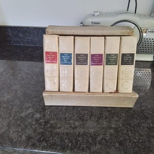 Könnte beinhalten: Ein Satz von sieben antiken gebundenen Büchern mit weißen Einbänden und goldenen Lettern. Die Titel lauten "The Reader's Book of Riddles", "The Reader's Book of Adventure", "The Reader's Book of Laughter", "The Reader's Book of Encounters", "The Reader's Book of Nature", "The Reader's Book of the Art of Home".