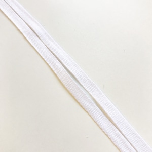 May include: Two white shoelaces are diagonally positioned against a white background. The laces are flat and woven, with a slightly textured appearance. The image is a close-up, highlighting the details of the shoelaces.