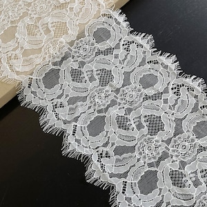 May include: White lace trim with a delicate floral pattern and scalloped edges.