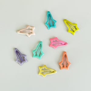 May include: Eight colorful star-shaped hair clips in various colors, including pink, blue, green, and yellow.