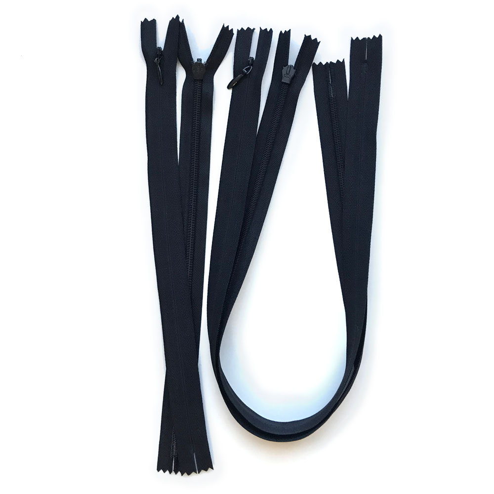 May include: Several black zippers of varying lengths are arranged on a white background. The zippers are closed and open, showcasing the teeth and pull tabs. The fabric is a solid black color.