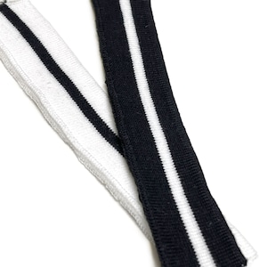 Könnte beinhalten: Zwei Stücke schwarzes und weißes gestreiftes Gummiband. Ein Stück ist weiß mit schwarzen Streifen und das andere ist schwarz mit weißen Streifen.