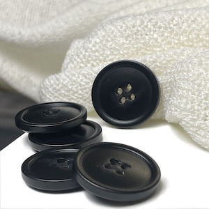May include: Five black plastic buttons with four holes each. The buttons are round and have a smooth, glossy finish.