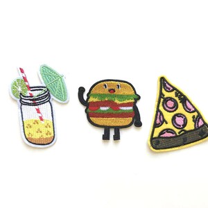 Könnte beinhalten: Drei gestickte Bügelbilder mit einem Cartoon-Burger, einem Stück Pizza und einem Glas Limonade mit Strohhalm und einem Limettenstück. Die Patches sind gelb, grün, rot und pink.
