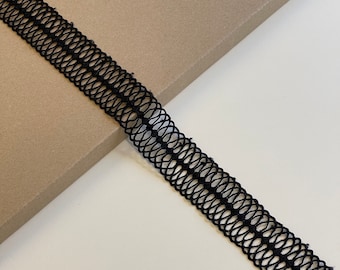 May include: Black elastic trim with a delicate, openwork design. The trim is made of a soft, flexible material and has a slightly textured surface.
