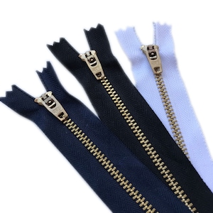 May include: Three zipper tapes with gold metal teeth. The tapes are black, navy blue, and white.