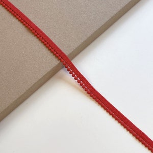 May include: Red trim with small pom poms along the edge.