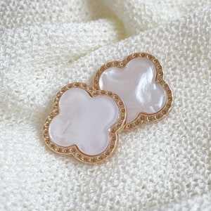 Peut inclure: Deux broches en forme de trèfle dorées avec des centres nacrés blancs.