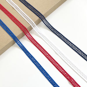 Puede incluir: Cuatro carretes de encaje blanco, rojo, azul y azul marino. El encaje tiene un diseño delicado y calado.