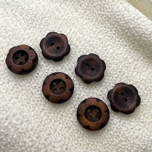 May include: Six brown wooden buttons in a flower shape with four holes each.