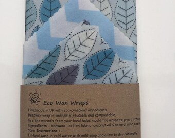May include: Two eco-friendly beeswax food wraps with a blue and white leaf pattern and a blue and white chevron pattern. The wraps are made with beeswax, cotton fabric, coconut oil, and natural pine resin. The text on the label reads: "Eco Wax Wraps Handmade in UK with eco-conscious ingredients. Beeswax wrap is washable, reusable and compostable. Use the warmth from your hand helps mould the wraps to give a strong seal. Ingredients: beeswax, cotton fabric, coconut oil & natural pine resin. Care Instructions: 1) Hand wash in cold water with mild soap and allow to dry naturally. 2) Do not use on raw meat. 3) Not suitable for hot water, dishwasher, microwave or direct heat. Contact: etradez@gmail.com"