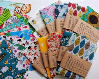 May include: Assortment of colorful fabric food wraps with floral, geometric, and animal print designs. The wraps are made with beeswax, jojoba oil, and tree resin. Each wrap has a brown paper label with the text "Eco Wax Wraps" and instructions for use.