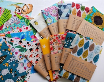 May include: A collection of colorful eco wax wraps with various patterns, including floral, geometric, and animal prints. The wraps are made with beeswax, jojoba oil, and tree resin. Each wrap is labeled with "Eco Wax Wraps" and instructions for care and use.