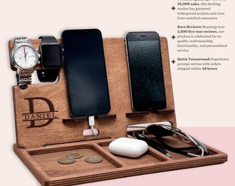 May include: A dark walnut wood docking station with a personalized name "DANIEL" engraved on the front. The station has slots for two phones, a watch, and a pair of glasses. There are also two small compartments for keys or other small items.