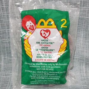 Könnte beinhalten: Versiegelter Plastikbeutel mit einem McDonald's Ty-Spielzeug. Der Beutel ist grün mit einem gelb-roten Logo mit Ronald McDonald. Der Text enthält "ANTSY - THE ANTEATER" und "NICHT ZUM WEITERVERKAUF". Eine 2 ist sichtbar.