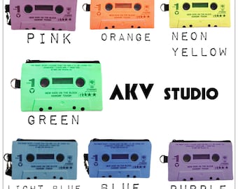 May include: A set of ten cassette tape-shaped zippered pouches in various colors, including pink, orange, neon yellow, green, light blue, blue, and purple. Each pouch features the text "NEW KIDS ON THE BLOCK HANGIN' TOUGH" and a star rating.