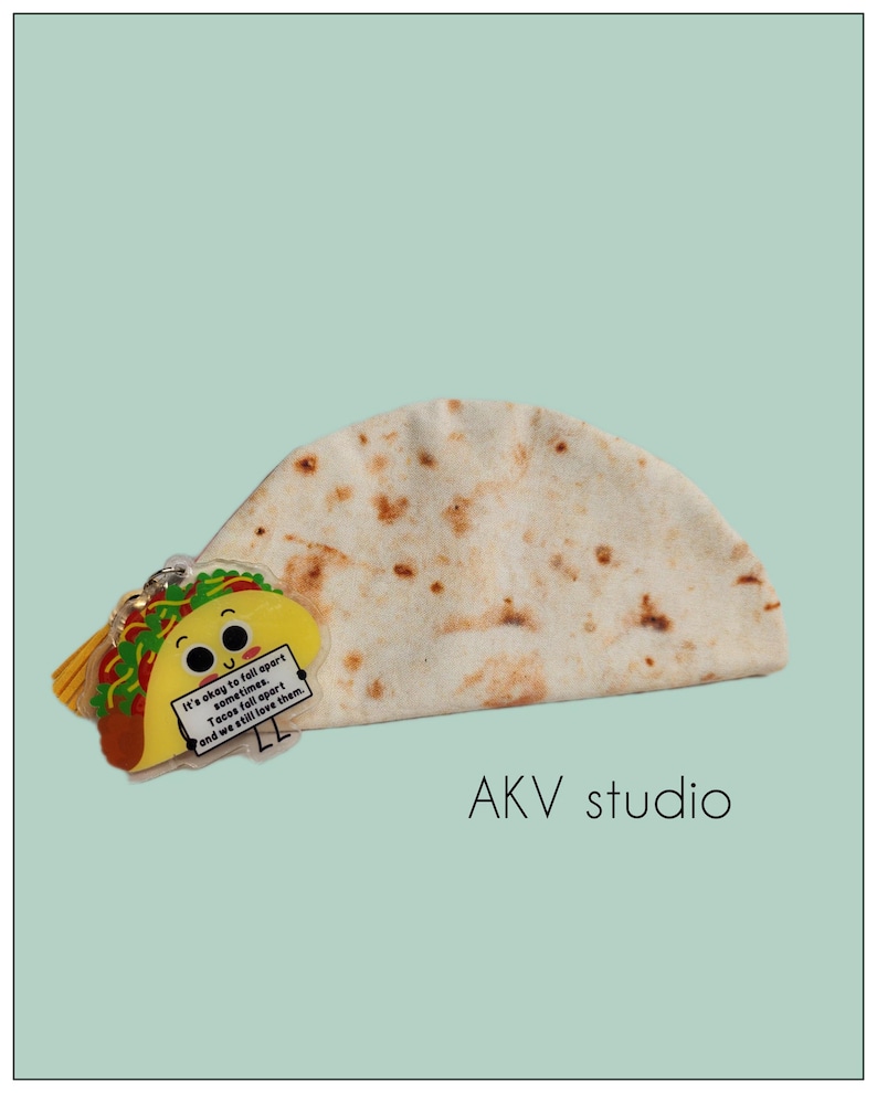 May include: A whimsical image featuring a tortilla and a taco-shaped keychain. The keychain has a smiling face and a sign that reads, "It's okay to fall apart sometimes. Tacos fall apart and we still love them." The background is a light teal color.