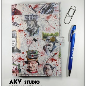 May include: A white leather notebook with a colorful print of horror movie characters and scenes. The notebook has a red, white, and blue color scheme and features a variety of characters, including Freddy Krueger, Jason Voorhees, Michael Myers, and more. The notebook also has a gold button and a strap.