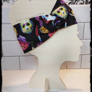 May include: A black fabric headband with a colorful print of horror movie characters and knives. The headband is tied in a knot on a wooden mannequin head. The text "HTTPS://LINKTR.EE/AKVSTUDIO" is printed on the headband.