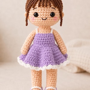 May include: A handmade crochet doll with light skin, black eyes, and brown yarn hair styled in a bun with bangs. The doll wears a purple dress with thin white straps and a white scalloped hem, paired with matching purple shoes featuring white accents.