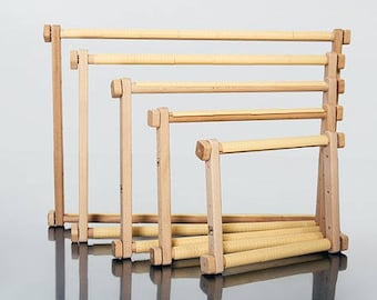 May include: A set of four wooden embroidery hoops of varying sizes. The hoops are made of light-colored wood and are arranged in a staggered formation, showcasing their different dimensions. The design is simple and functional, suitable for needlework projects.