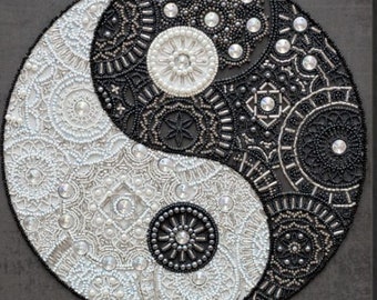 Op de afbeelding: Een zwart-wit yin yang symbool gemaakt van kralen. Het symbool is omgeven door een grijze achtergrond. Het symbool is een populair symbool van balans en harmonie.