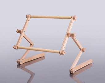 May include: A wooden embroidery stand with adjustable legs and a horizontal bar for stretching fabric. The stand is made of natural wood and has a light brown finish.