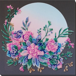 May include: A beaded floral design with pink, blue, and green flowers on a gray background. The flowers are arranged in a circle around a light blue and pink gradient.