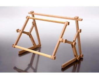 May include: A wooden embroidery stand with adjustable height and angle. The stand has two horizontal bars for holding fabric and a base with legs.