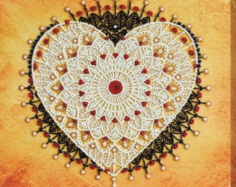 Op de afbeelding: Een hartvormige mandala met witte, zwarte en rode kralen. De mandala is omgeven door een zwarte en witte kralenrand.
