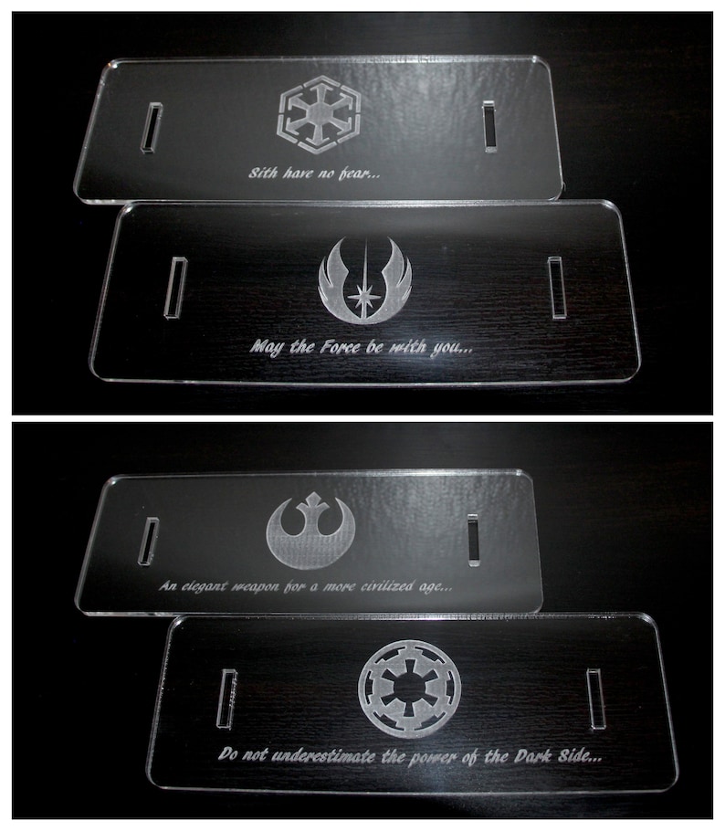 May include: Four clear acrylic plaques with engraved designs and text. The top plaque features a symbol and the text "Sith have no fear...". The second plaque has a symbol and the text "May the Force be with you...". The third plaque has a symbol and the text "An elegant weapon for a more civilized age...". The fourth plaque has a symbol and the text "Do not underestimate the power of the Dark Side..."