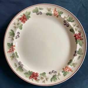 May include: A white ceramic dinner plate with a red, green, and black berry design around the rim.