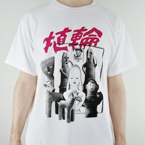 May include: White t-shirt featuring a black and white graphic print of figures and the text "超音" in pink.