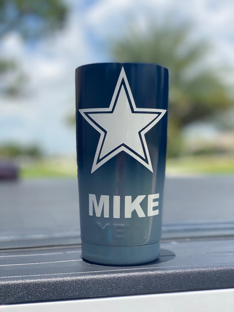 May include: A blue and gray tumbler with a white star and the name "MIKE" printed on it.