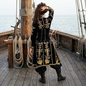 model holding her hair up and facing away is showing the back of her Elizabeth Swann costume. she is standing on a pirate ship deck