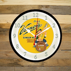 May include: A round clock with a black frame and a white face. The clock face features a yellow background with a vintage advertisement for Vernor's Ginger Ale. The ad features a cartoon leprechaun holding a bottle of Vernor's Ginger Ale. The clock face also includes black Roman numeral hour markers and a red second hand.