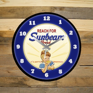 May include: A blue and white clock with a vintage Sunbeam Bread advertisement. The clock face features a girl eating a slice of bread with the text "Reach for Sunbeam Bread" and "It's Batter Whipped!"