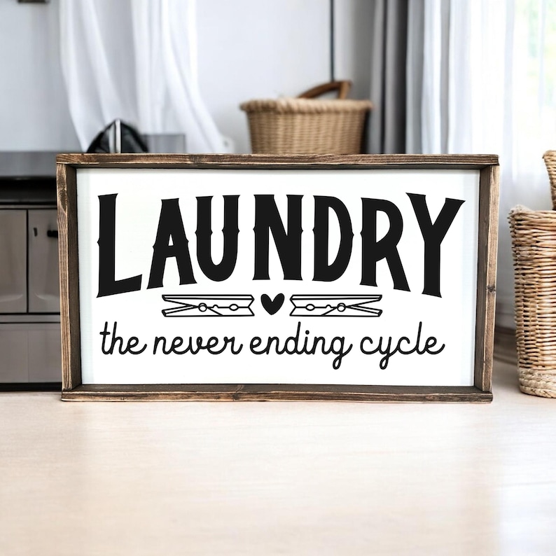 K&ouml;nnte beinhalten: Ein Holzschild mit dem Text "Laundry the never ending cycle" in schwarzen Buchstaben. Das Schild hat einen rustikalen braunen Rahmen und einen wei&szlig;en Hintergrund.