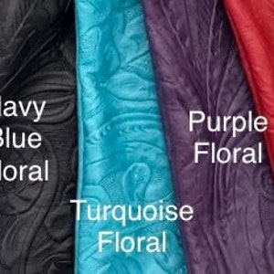 May include: A selection of eight leather swatches with embossed floral patterns in various colors, including black, brown, navy blue, turquoise, purple, red, and tan.
