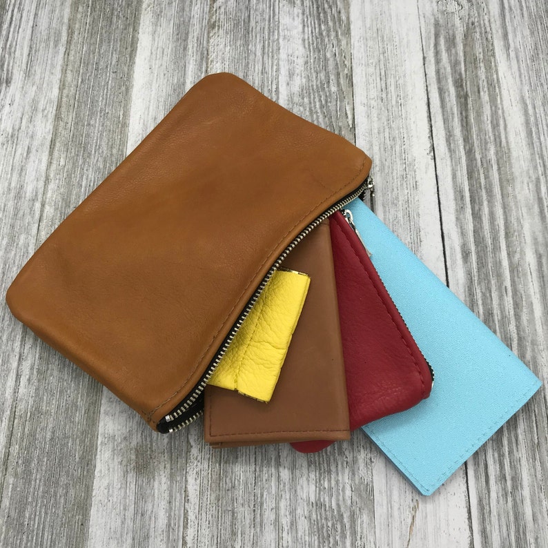 May include: A brown leather zippered pouch with four smaller pouches inside. The smaller pouches are yellow, brown, red, and light blue.