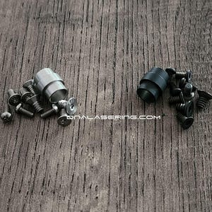 May include: Two sets of hardware components, each featuring a cylindrical metal spacer and several small screws. One set is silver-toned, and the other is matte black. The text ONALASERING.COM is printed in white between the two hardware groupings.