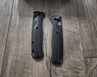 May include: Two black knife scales with a textured pattern. The scales are made of a durable material and are designed to fit a Benchmade knife.