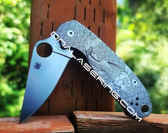 May include: A silver pocket knife with a black handle and a koi fish design. The knife is open and the blade is visible.